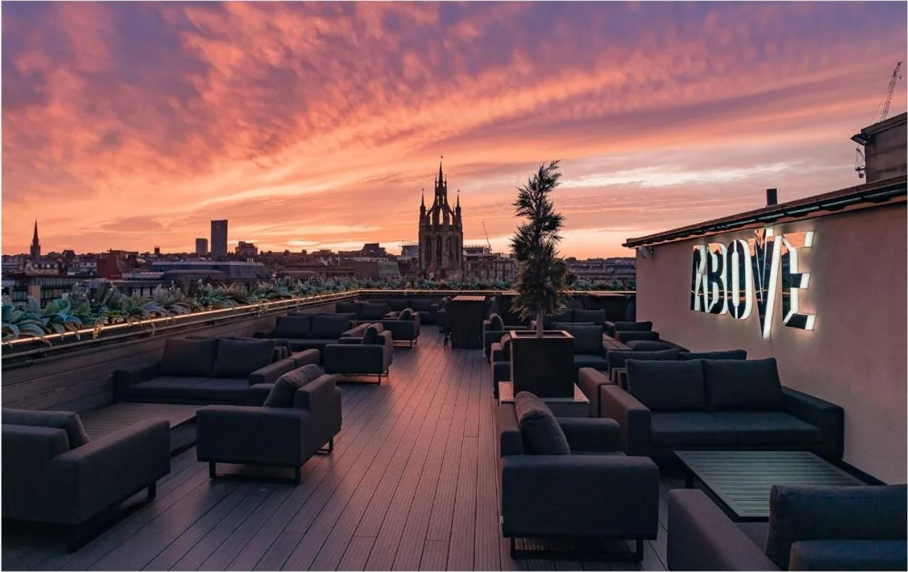 a rooftop deck with couches and a sunset at The Vermont Hotel Newcastle in Newcastle upon Tyne